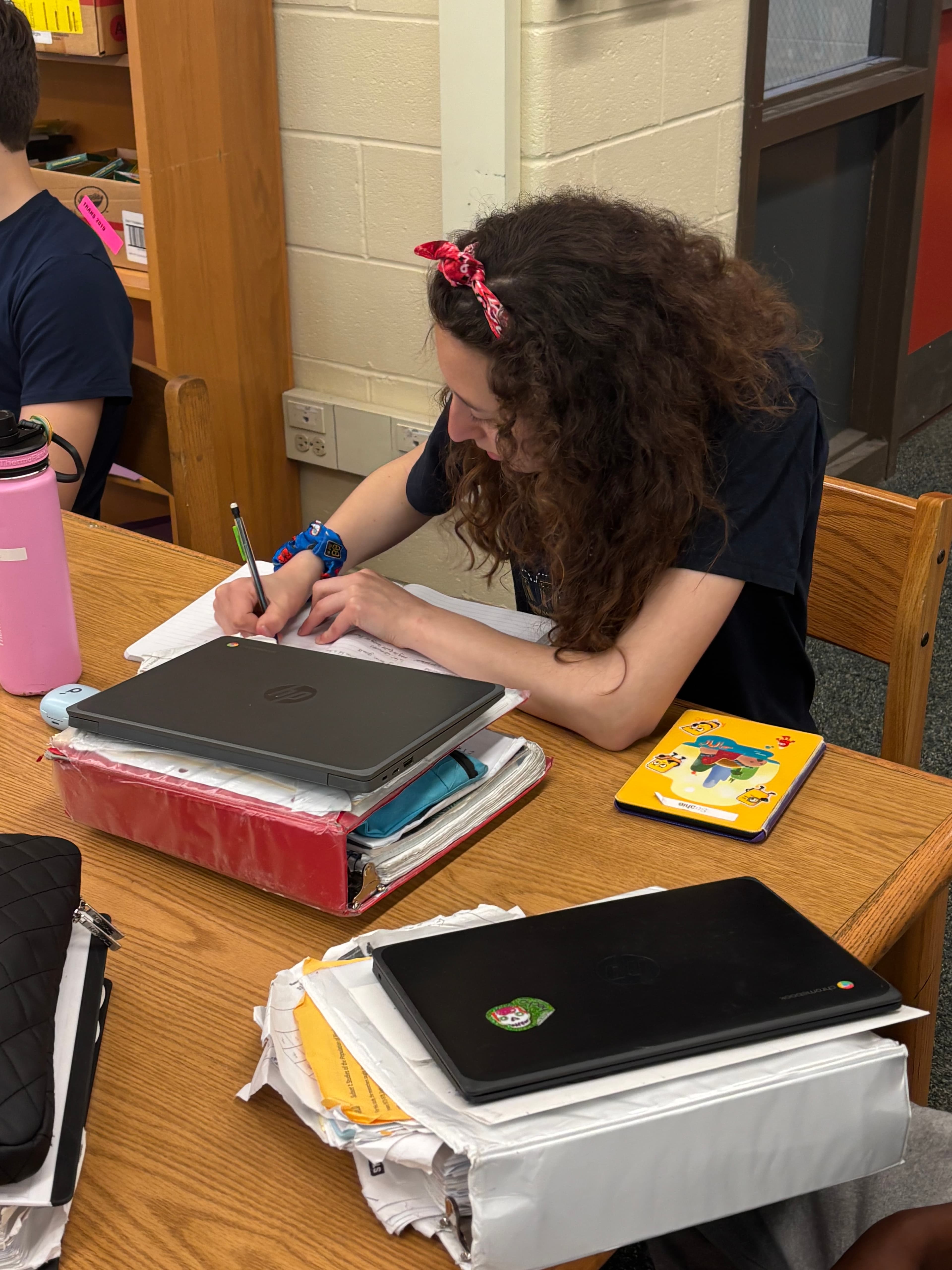An eighth grader taking notes at her desk during the Compass financial literacy lesson at Bigelow Middle School.