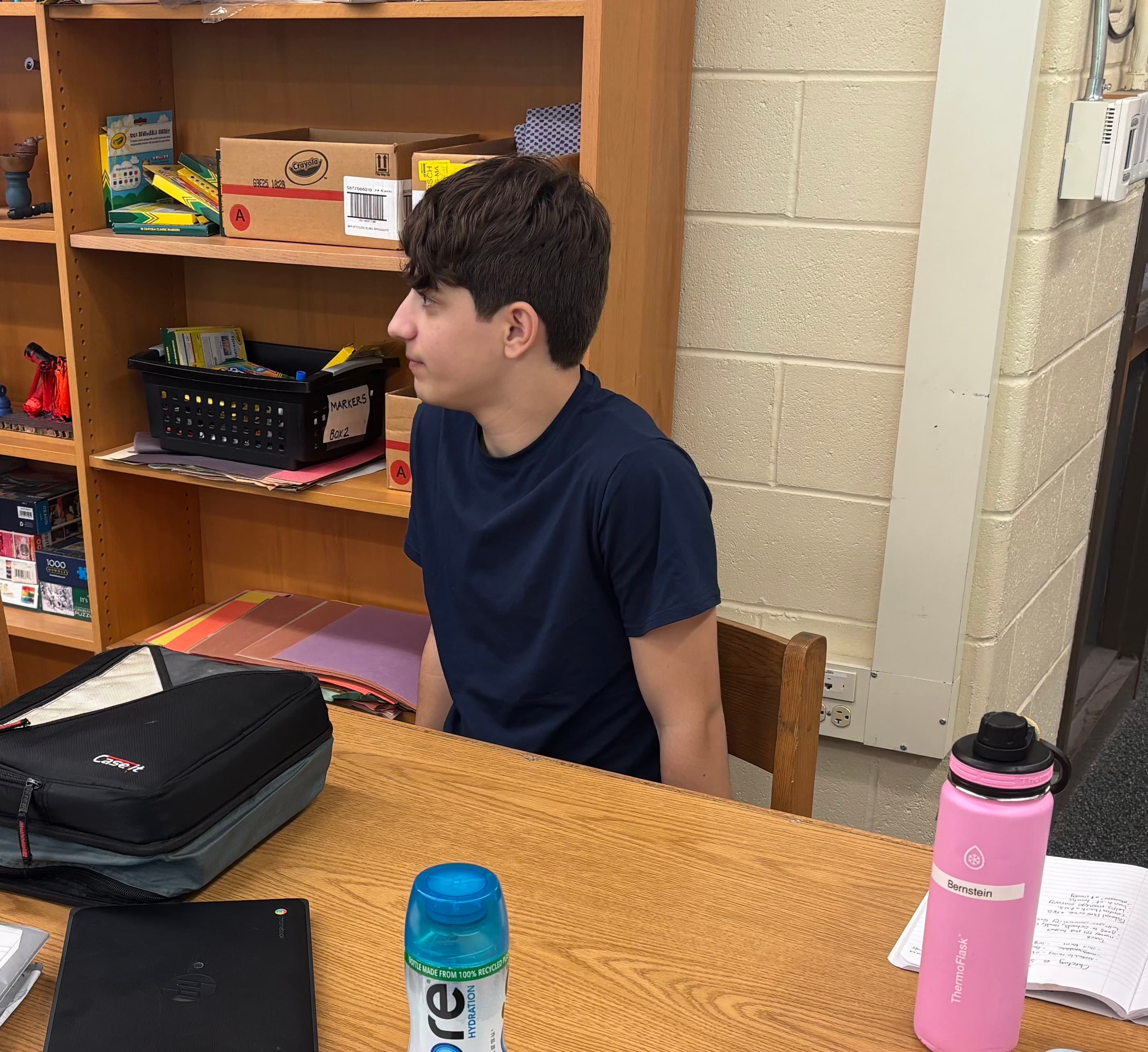 An eighth grader listening attentively from his desk during the Compass presentation.