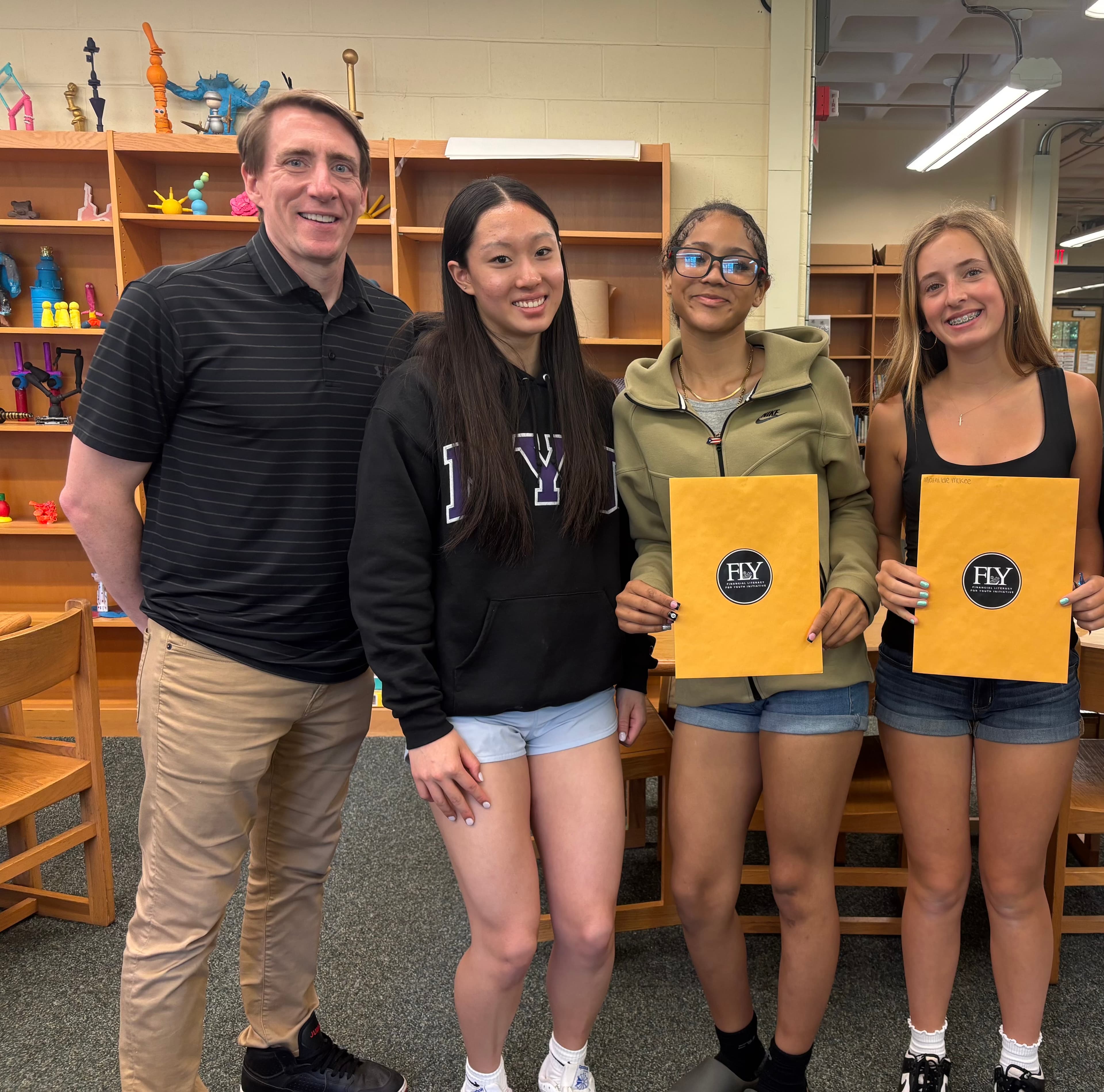 A Bigelow Middle School teacher with three eighth graders, two holding Compass program envelopes, after the visit.