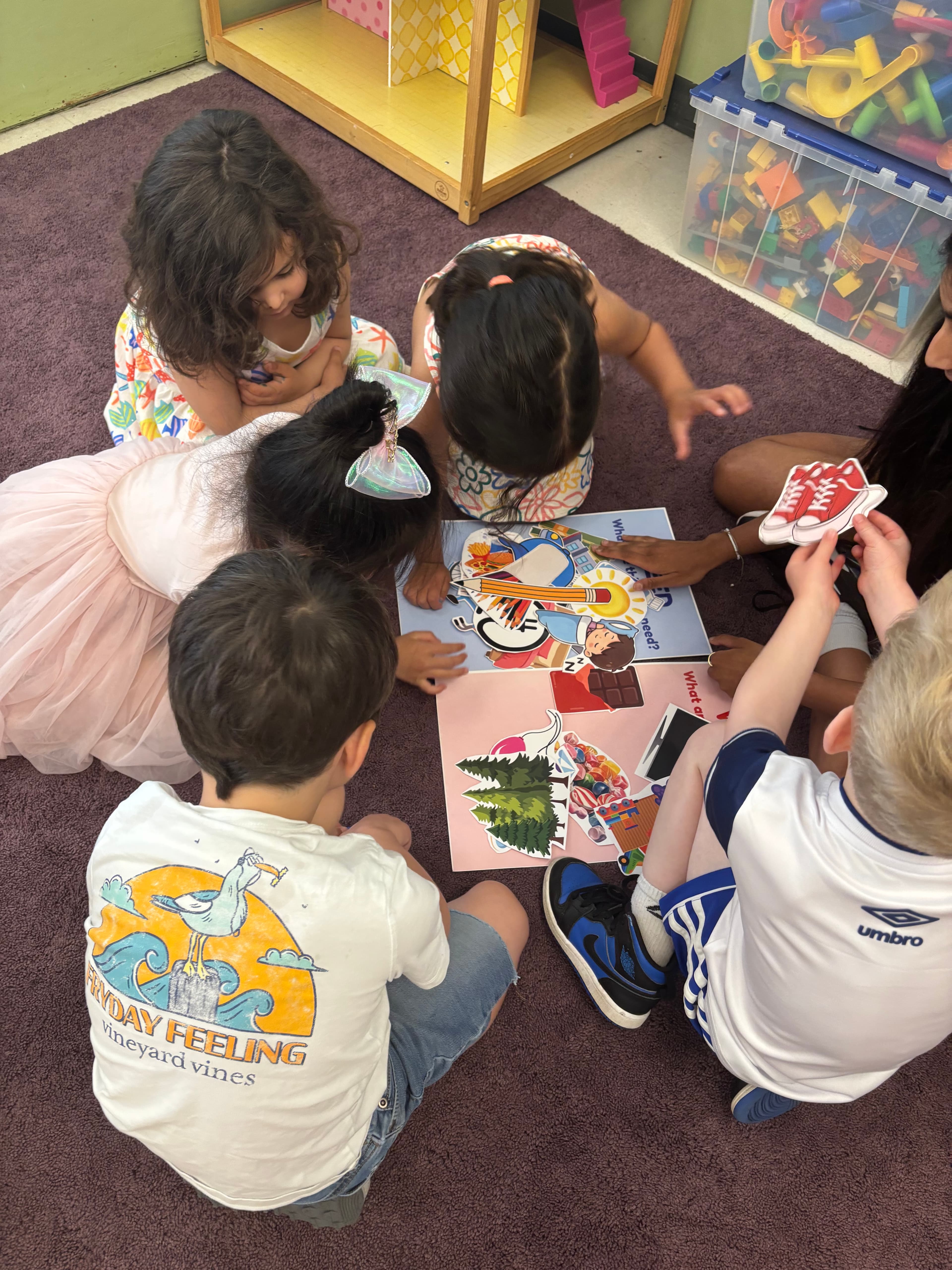 Preschoolers sorting picture cards into needs and wants during a group activity.
